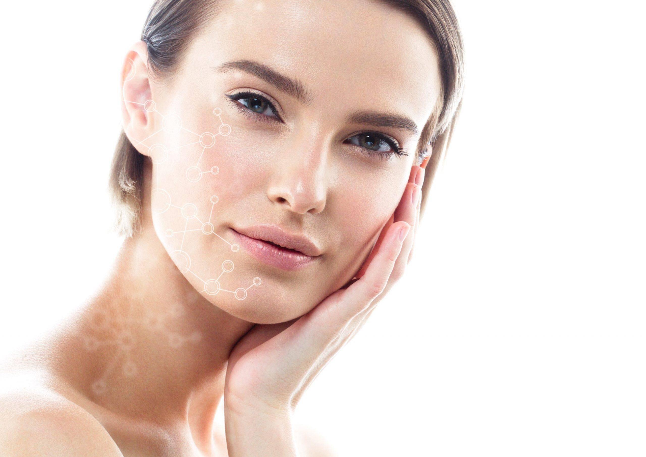 A woman with clear skin gently touching her face with one hand, looking directly at the camera. A subtle overlay of molecular structures is superimposed on her cheek, suggesting a focus on skincare or beauty technology. The background is white and minimalistic.