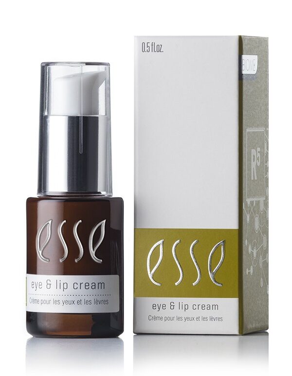 A brown bottle of Esse Eye & Lip Cream with a white pump dispenser is displayed next to its white and green box packaging. The text on the bottle and box reads "Esse Eye & Lip Cream - Crème pour les yeux et les lèvres." The bottle contains 0.5 fl oz of product.
