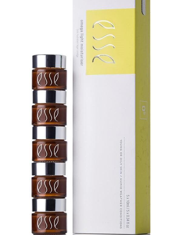 A stack of five brown jars with silver lids next to a white and yellow box labeled "Esse Omega Rich Moisturiser." Both the jars and the box display the "Esse" logo. The box also mentions that the product is for young or oily skin with mildly impaired barrier function.