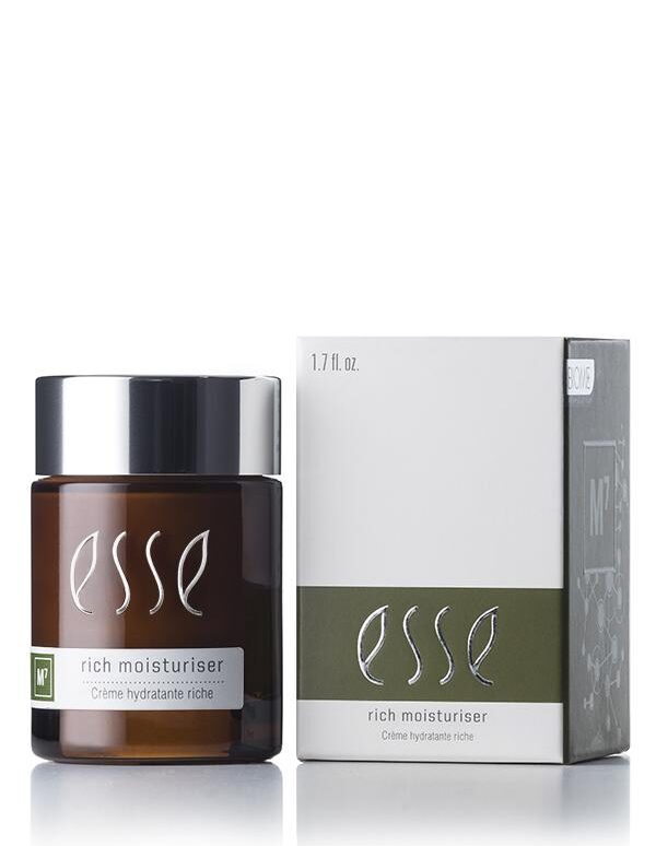A jar of Esse Rich Moisturiser is displayed beside its packaging. The jar is dark brown, topped with a sleek black lid and adorned with white text. Its accompanying white box showcases the brand logo and product name prominently, highlighted by a green accent stripe near the bottom that includes additional information.