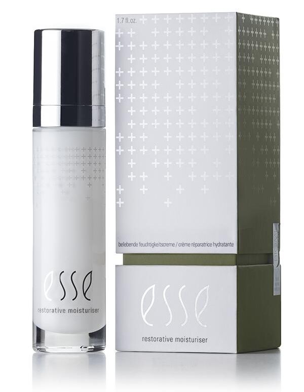 A product shot of Esse Restorative Moisturiser. The image features a white bottle with a silver cap placed beside its rectangular grey-and-green packaging. Both the bottle and the box display the Esse logo and product name in white text, complementing their minimalist design.