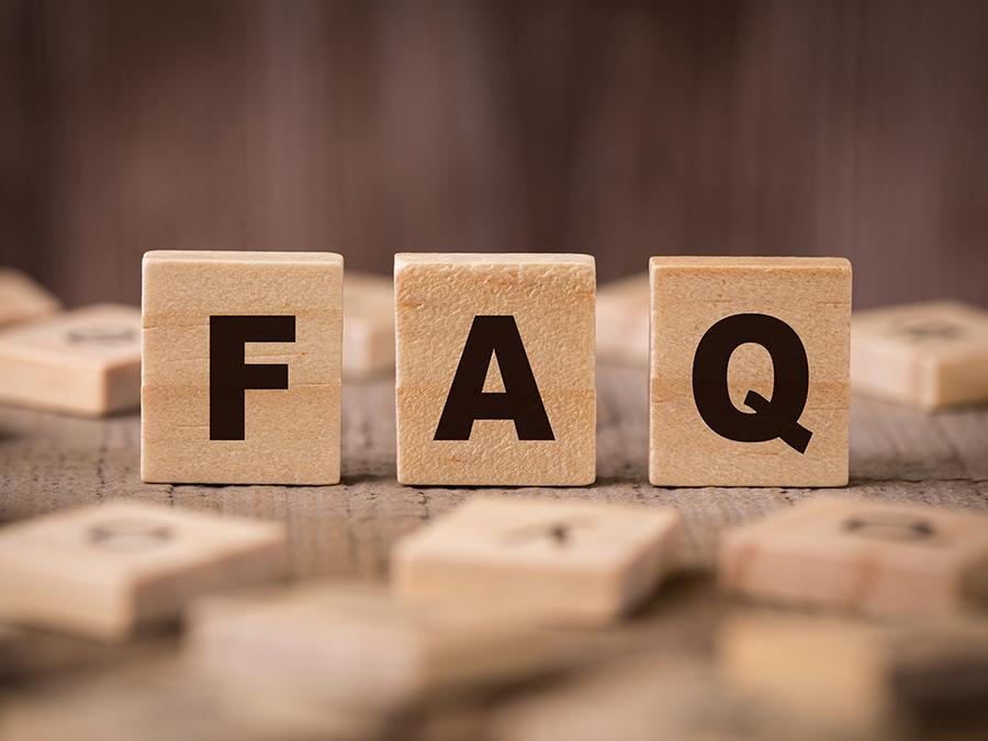 Wooden blocks with the letters "F," "A," and "Q" displayed prominently on them, standing on a wooden surface. The background consists of other blurred wooden blocks scattered around.