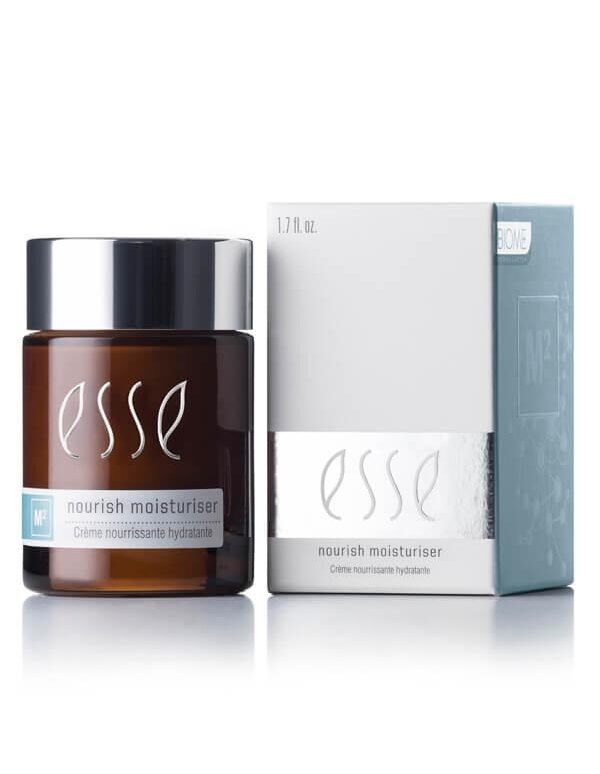 A brown glass jar of Esse Nourish Moisturiser is displayed next to its silver and white rectangular box. The jar has a silver lid and features the product name and details in white and blue text. The box showcases similar branding and text.